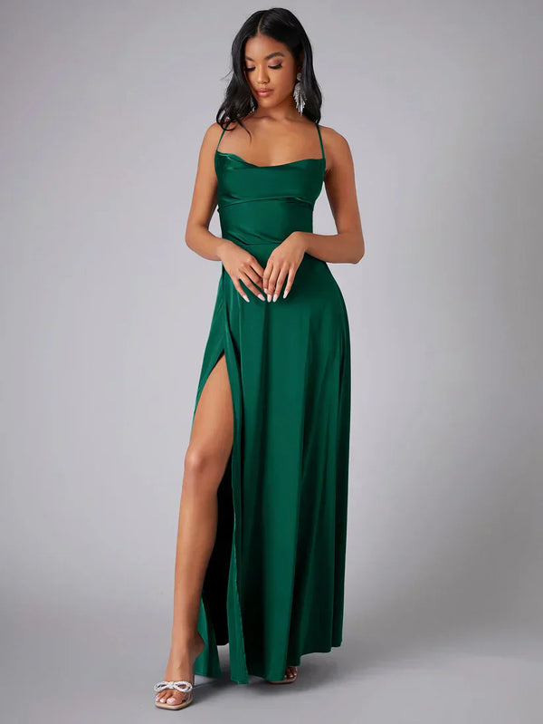 Femme portant une robe longue verte élégante avec une fente haute, posant sur fond neutre. Mode féminine, robe de soirée, style chic.
