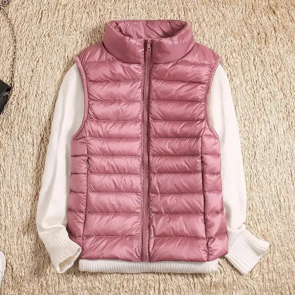 Gilet matelassé rose sans manches sur pull blanc, posé sur tapis beige. Mode automne-hiver, vêtements chauds, style décontracté et tendance.