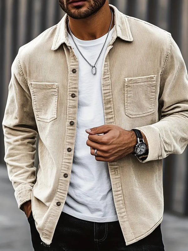 Homme portant une chemise en velours côtelé beige, t-shirt blanc, montre noire et chaîne argentée. Mode masculine élégante et décontractée.