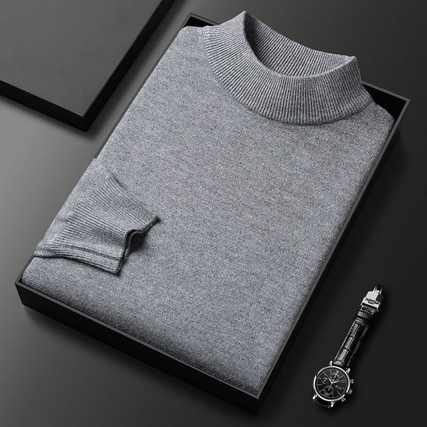 Pull-over gris en laine plié dans une boîte noire, accompagné d'une montre-bracelet élégante sur fond noir. Mode homme, vêtements d'hiver.
