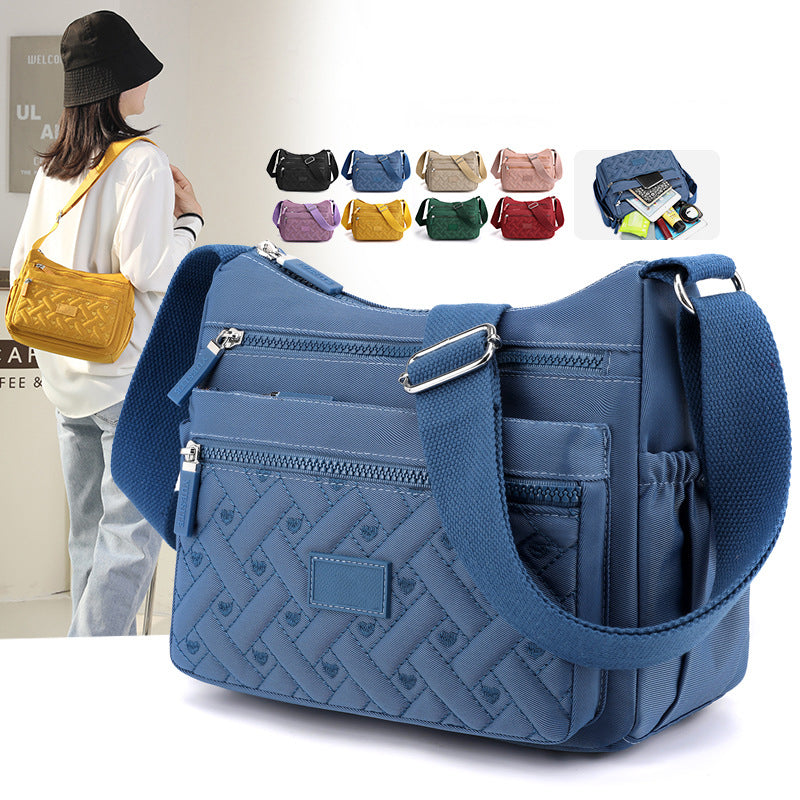 Sac à bandoulière bleu en tissu avec poches zippées, design tressé, et bandoulière réglable. Disponible en plusieurs couleurs. Accessoire mode tendance.