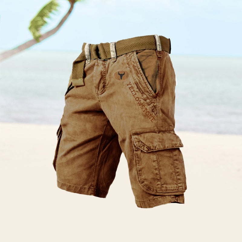 Short cargo marron avec ceinture, poches latérales, motif Yellowstone, sur fond de plage tropicale. Mode estivale, vêtements décontractés pour homme.