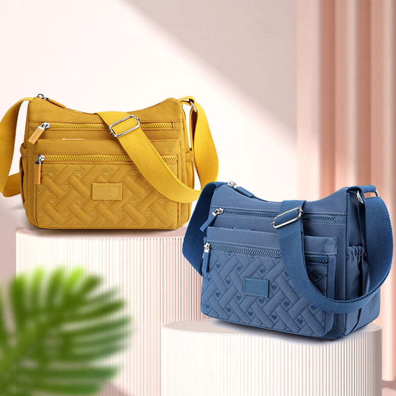 Deux sacs à bandoulière en tissu, jaune et bleu, avec poches zippées, posés sur des socles. Accessoires de mode tendance pour femmes.