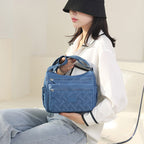 Femme assise avec un sac à main bleu en cuir texturé, portant un chapeau noir et une chemise blanche. Mode féminine, accessoires élégants.