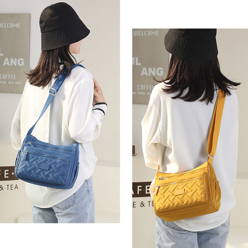 Femme portant un sac bandoulière en cuir tressé, bleu à gauche et jaune à droite, avec chapeau noir et chemise blanche. Mode tendance, accessoires élégants.