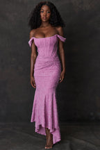 Robe longue en dentelle rose, épaules dénudées, portée par une femme sur fond sombre. Mode élégante, tenue de soirée chic, style glamour.