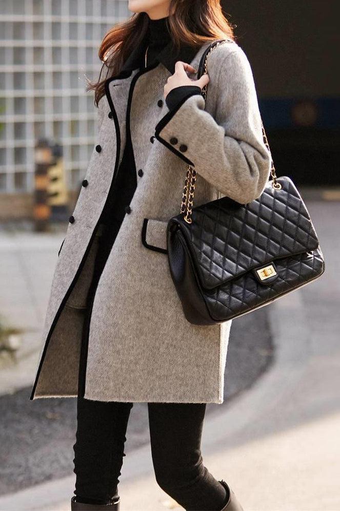 Femme portant un manteau gris élégant avec boutons noirs, sac à main matelassé noir à chaîne dorée, tenue chic automne-hiver, mode urbaine.