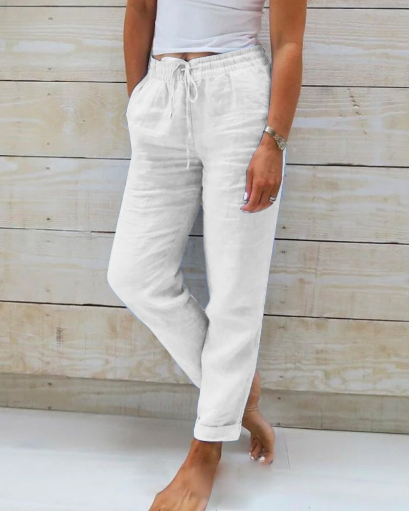 Pantalon en lin blanc pour femme, taille élastique avec cordon, poches latérales, style décontracté, fond en bois clair.