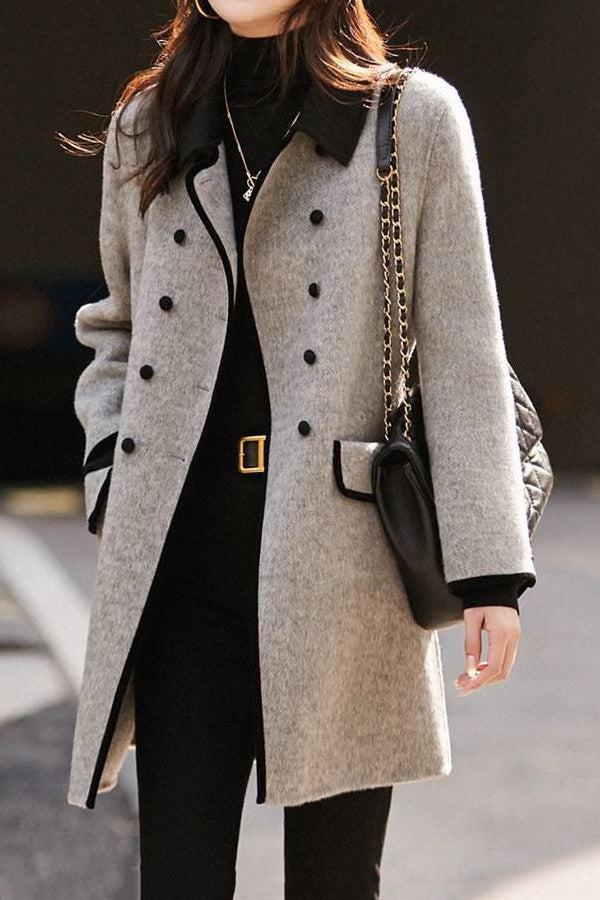 Femme portant un manteau gris élégant à double boutonnage, col noir, avec sac à bandoulière en cuir noir. Mode automne chic et tendance.
