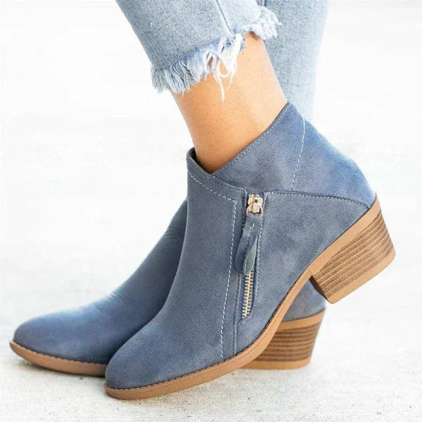 Bottines en daim bleu avec talon bloc en bois, fermeture éclair latérale, portées avec un jean déchiré. Chaussures tendance automne-hiver.