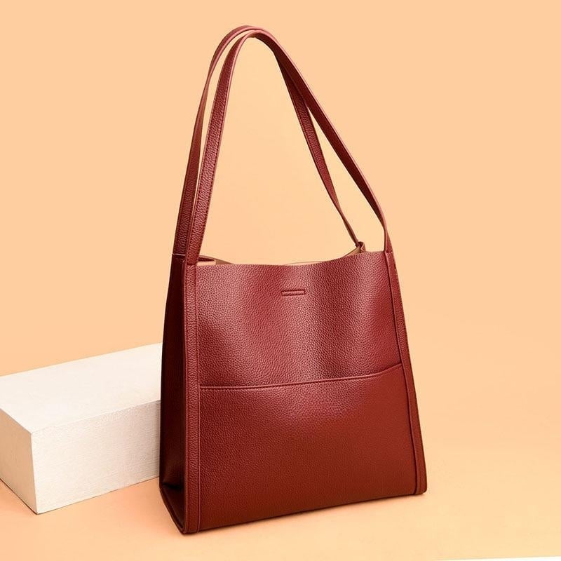 Sac à main en cuir marron élégant sur fond beige, design moderne avec anses longues. Accessoire mode femme, tendance et chic.