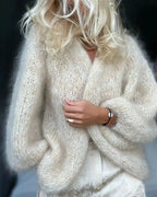Femme portant un pull en mohair beige, manches longues, texture douce et vaporeuse, style élégant et moderne, mode automne-hiver tendance.