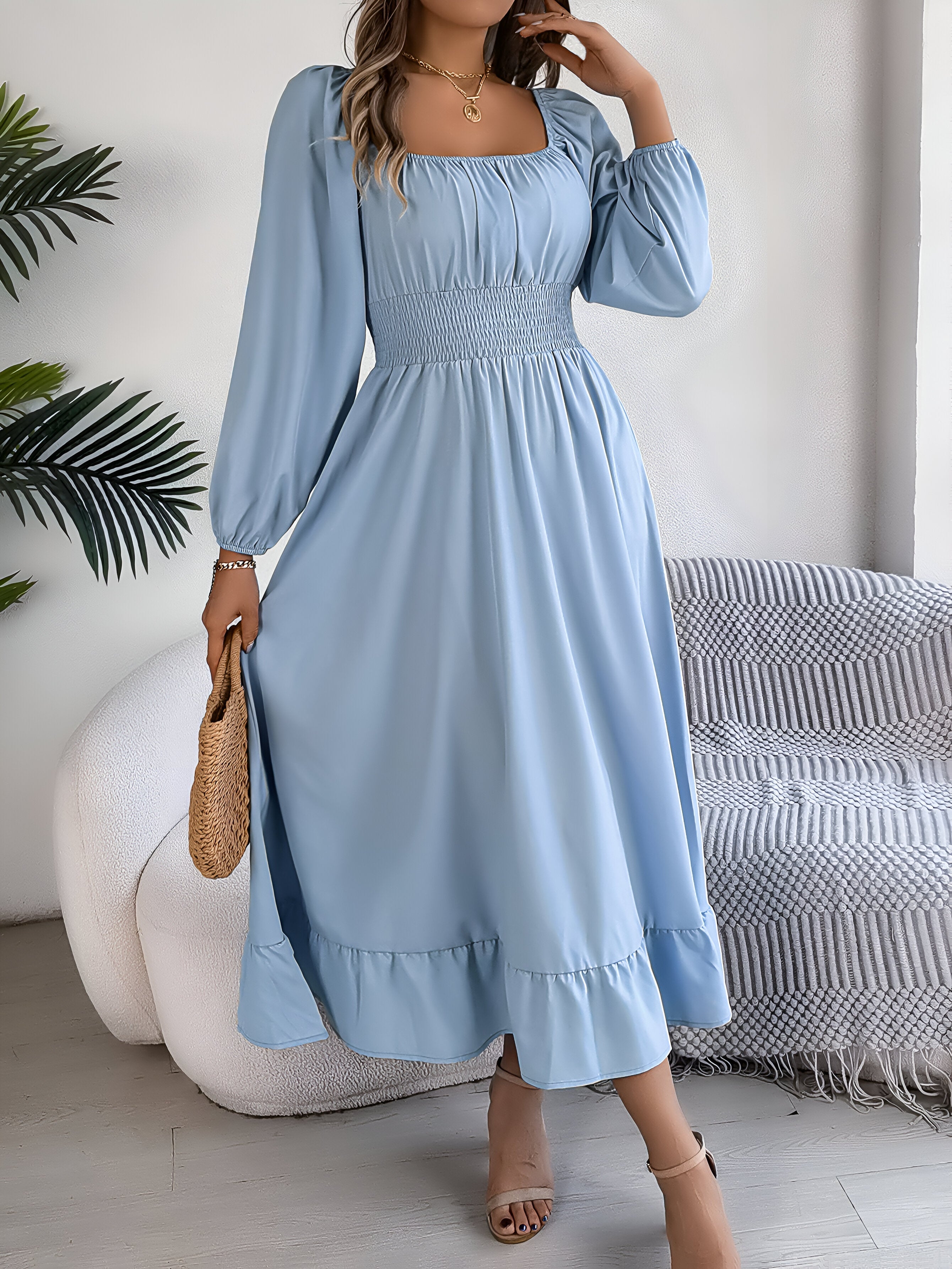 Robe longue bleue à manches longues, col carré, portée par une femme avec sac en osier. Style élégant et décontracté, idéal pour l'été.