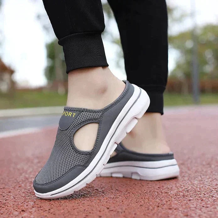 Chaussures de sport grises pour femme, semelle blanche, design aéré, portées sur une piste de course. Confort et style pour la marche active.
