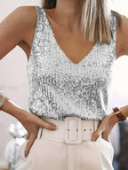 Femme portant un débardeur à paillettes argentées et un pantalon blanc avec ceinture. Mode élégante, tenue chic, style soirée.