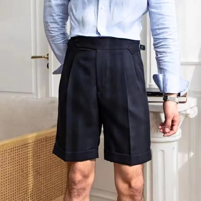 Homme portant un short élégant noir avec une chemise bleue, style moderne et chic, mode masculine, tenue estivale sophistiquée, intérieur raffiné.