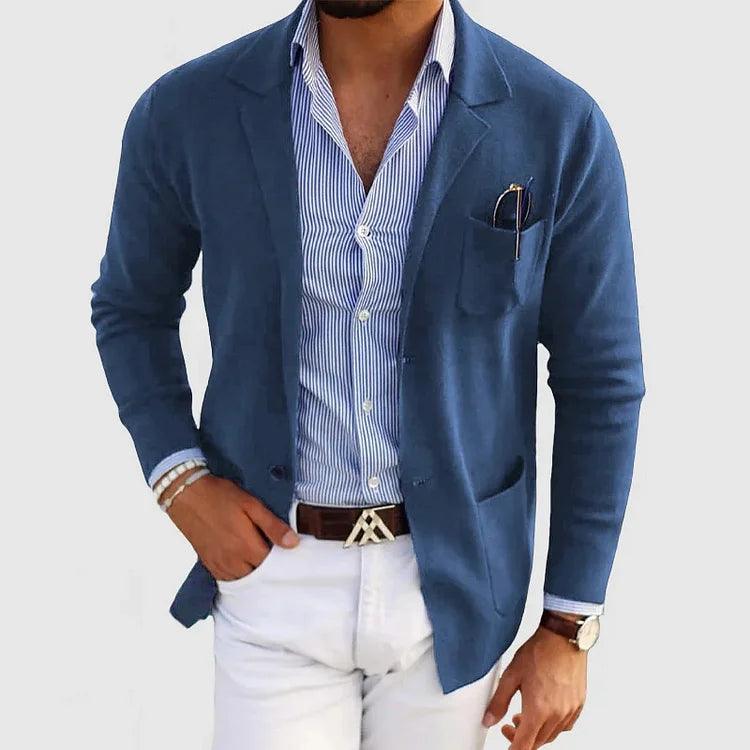 Homme en blazer bleu, chemise rayée bleue, pantalon blanc, ceinture marron, montre-bracelet, lunettes de soleil dans la poche, style élégant.