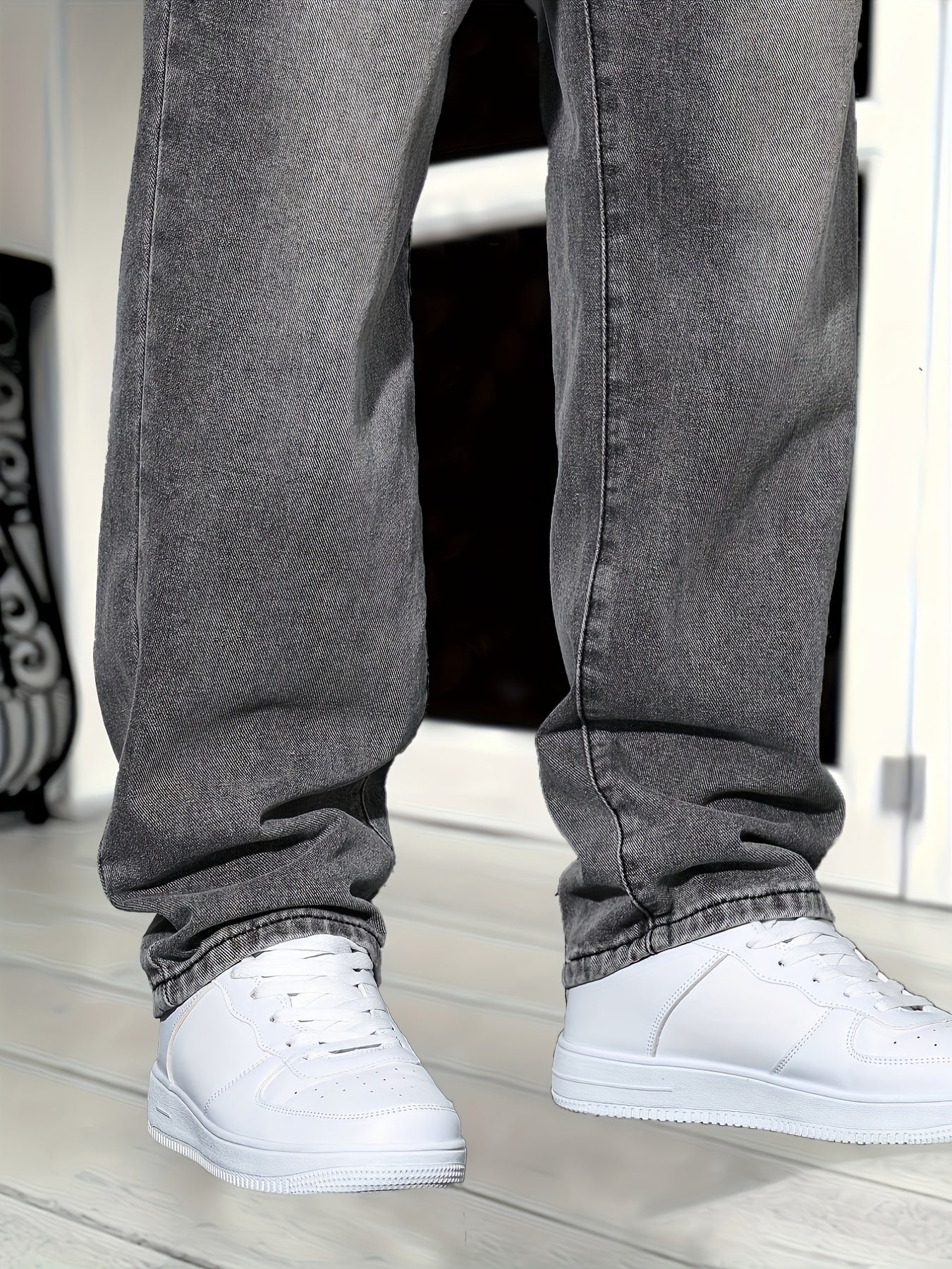 Jeans gris décontractés et baskets blanches sur parquet clair, style urbain moderne. Mode masculine, tendance streetwear, chaussures blanches.