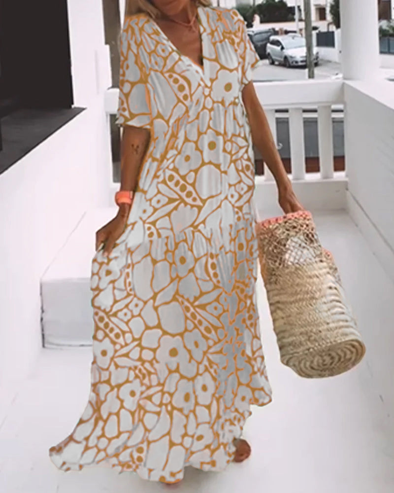 Robe longue bohème à motifs floraux orange et blanc, femme tenant un sac en osier, style estival décontracté, mode plage tendance.