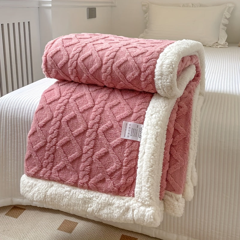 Couverture rose en peluche avec motif géométrique, bordée de fourrure blanche, posée sur un lit blanc. Accessoire de chambre cosy et élégant.