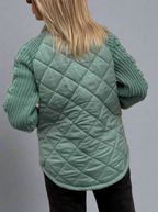 Veste matelassée verte pour femme avec manches en tricot, vue de dos. Mode automne-hiver, style décontracté, tendance vêtements chauds.