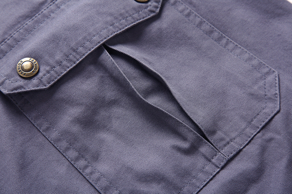 Poche de chemise en tissu gris avec bouton métallique, gros plan. Mode masculine, détails de couture, style décontracté, vêtement en coton.