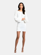 Robe blanche élégante à manches longues bouffantes, portée par une femme debout sur fond neutre. Mode féminine chic, tenue de soirée tendance.