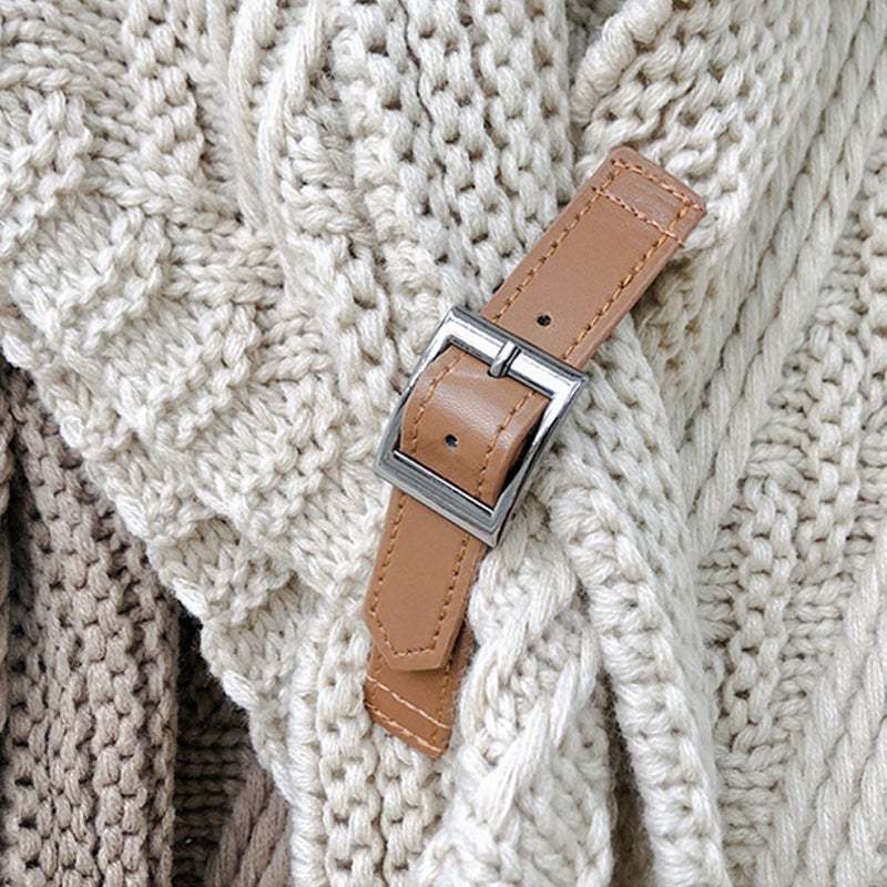 Ceinture en cuir marron avec boucle argentée posée sur un pull en tricot beige texturé. Accessoire mode élégant et tendance.