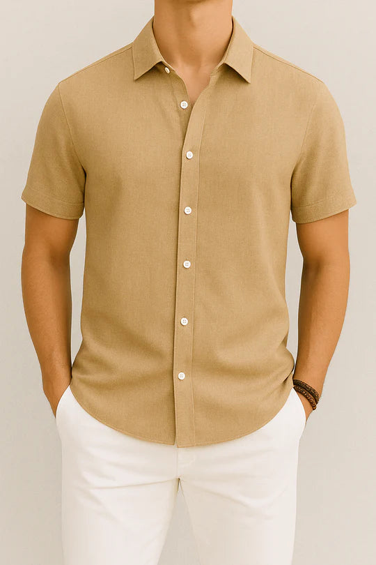 Chemise beige à manches courtes pour homme, élégante et décontractée, avec boutons blancs, portée avec un pantalon blanc. Mode masculine tendance.