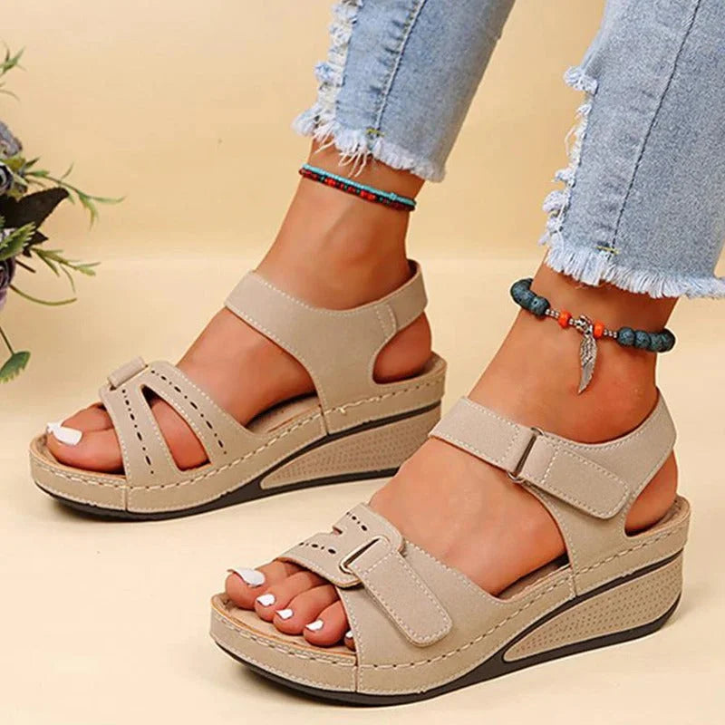 Sandales compensées beiges pour femme, portées avec un jean déchiré. Chaussures d'été élégantes, confortables, idéales pour un look décontracté.