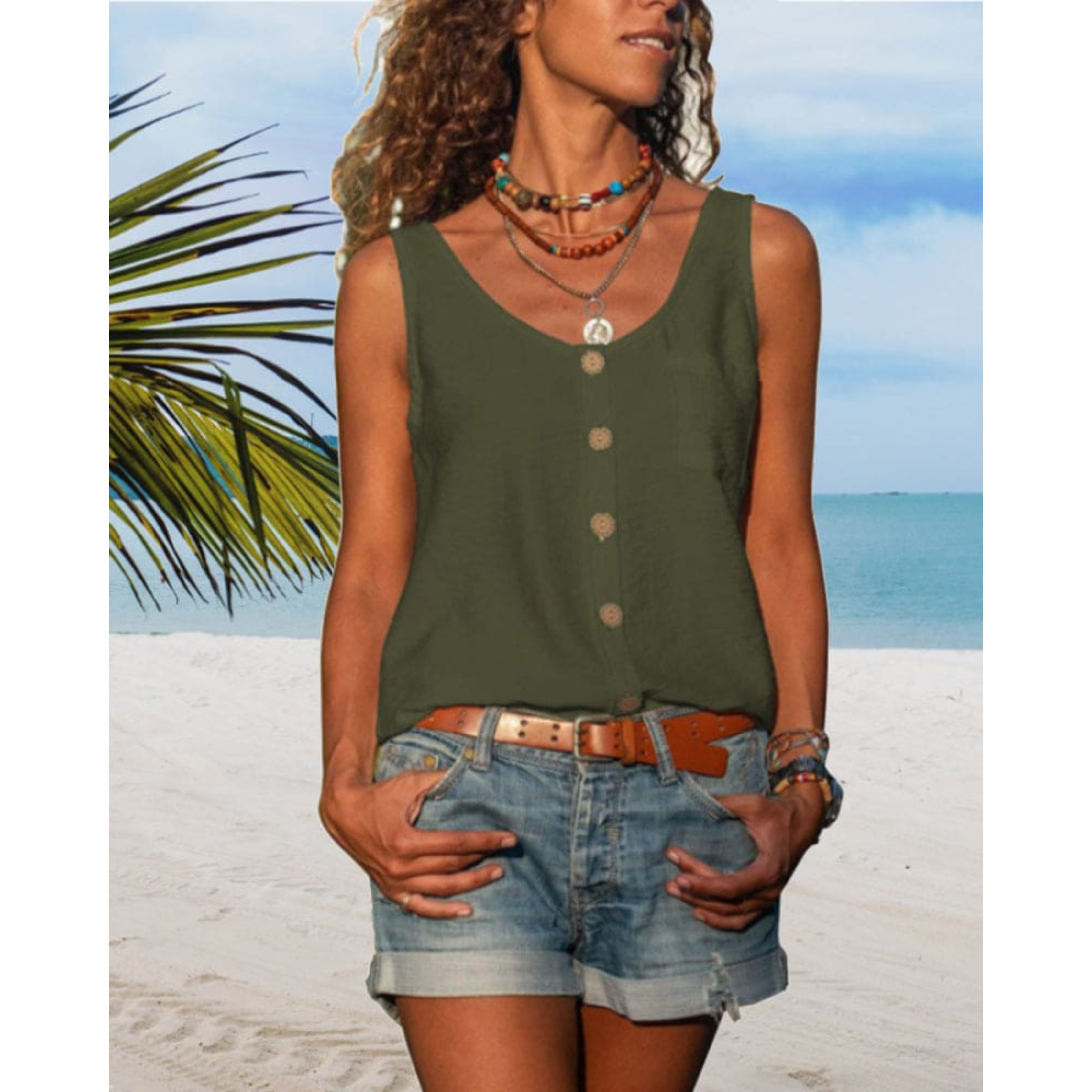 Femme en débardeur vert et short en jean sur plage tropicale, ciel bleu, palmiers. Mode estivale, vacances, style décontracté, bijoux colorés.