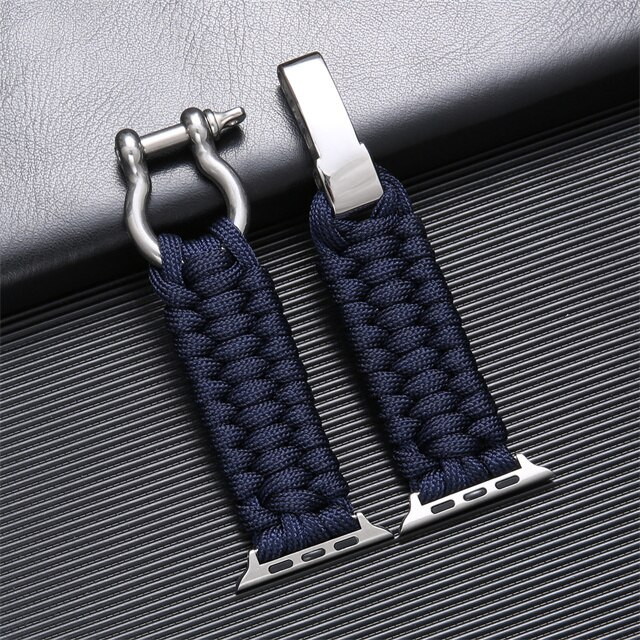 Bracelet de montre en paracorde bleu marine avec fermoirs en acier inoxydable, posé sur une surface texturée grise. Accessoire mode robuste et élégant.
