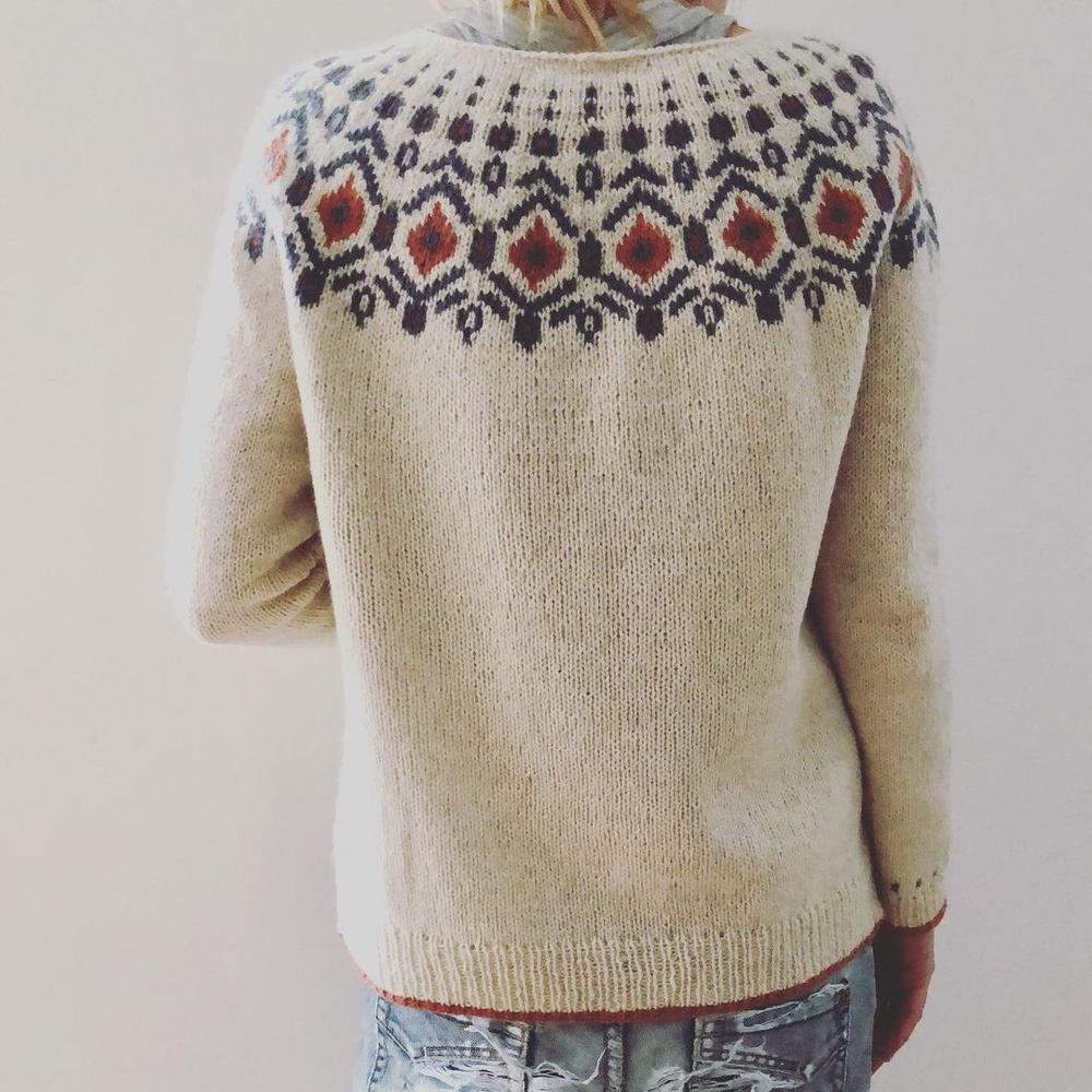Pull en laine beige avec motif nordique coloré sur le dos, porté par une personne de dos. Mode hiver, tricot artisanal, style scandinave.
