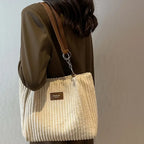 Sac à main en velours côtelé beige avec bandoulière marron, porté par une femme en manteau marron. Accessoire mode élégant et tendance.