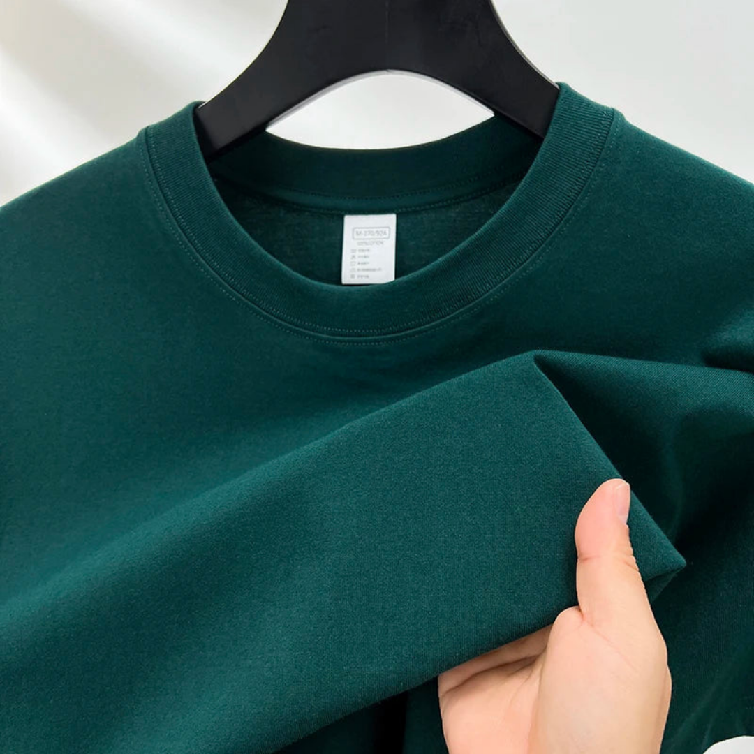 Sweat-shirt vert foncé en coton, suspendu sur un cintre noir, avec une main tenant la manche. Mode décontractée, vêtement unisexe, tissu doux.