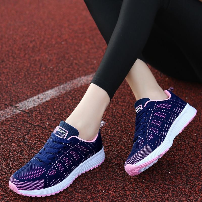 Baskets de course bleues et roses pour femme sur piste rouge, design moderne, semelle blanche, confortables et légères, idéales pour le sport.