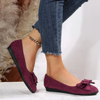 Ballerines en daim violet avec nœud, portées avec un jean bleu effiloché. Chaussures élégantes pour femme, mode automne, style décontracté.