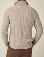 Homme portant un pull torsadé beige, manches longues, col montant, style élégant et décontracté, idéal pour l'automne et l'hiver.