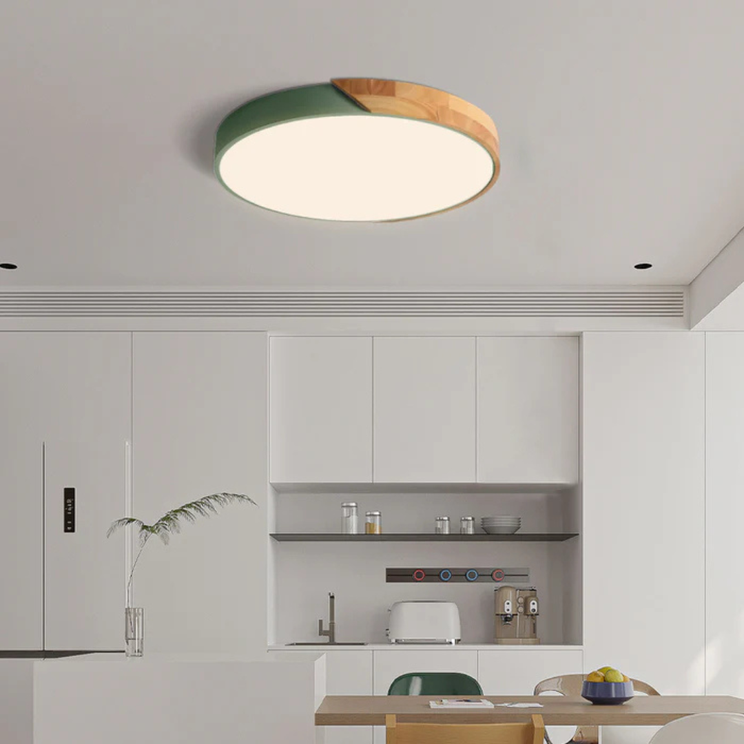 Plafonnier moderne rond en bois et vert dans une cuisine minimaliste blanche, éclairage LED, design contemporain, intérieur élégant et épuré.
