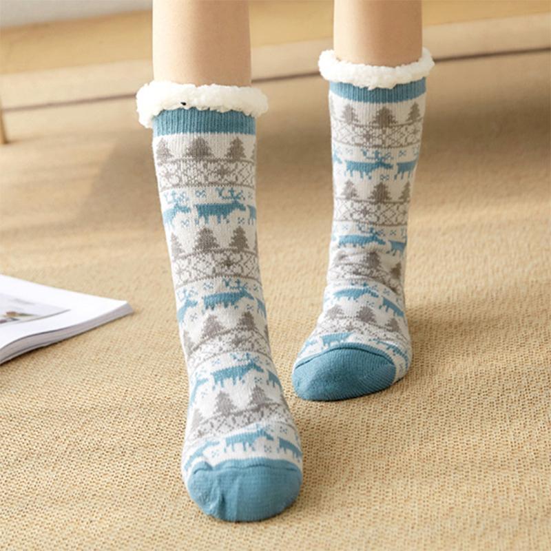 Chaussettes d'hiver en laine avec motifs nordiques bleus et gris, bordure en fourrure blanche, portées sur un tapis beige.