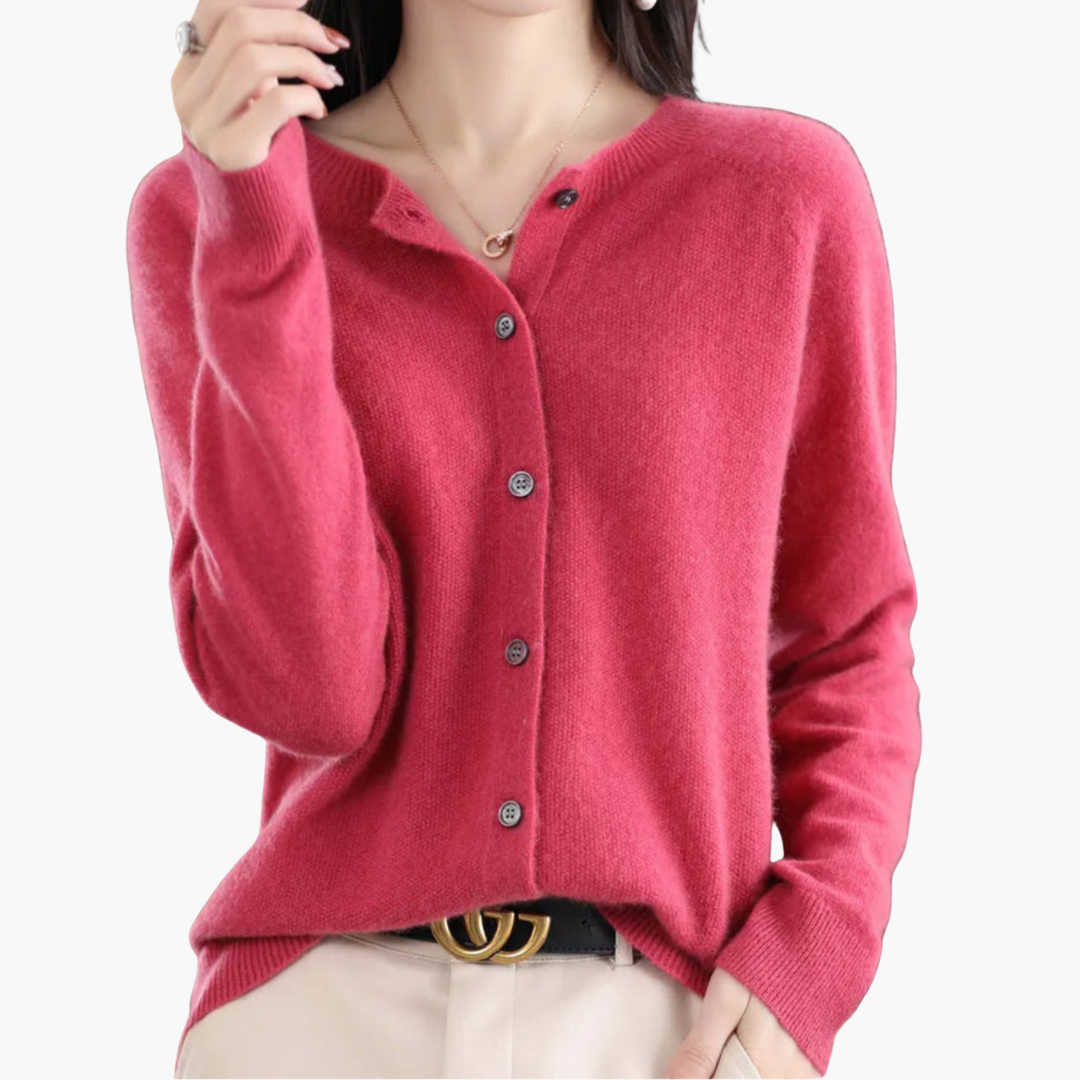 Femme portant un cardigan rose en cachemire, boutonné, avec un pantalon beige et une ceinture noire. Mode élégante et confortable pour l'automne.
