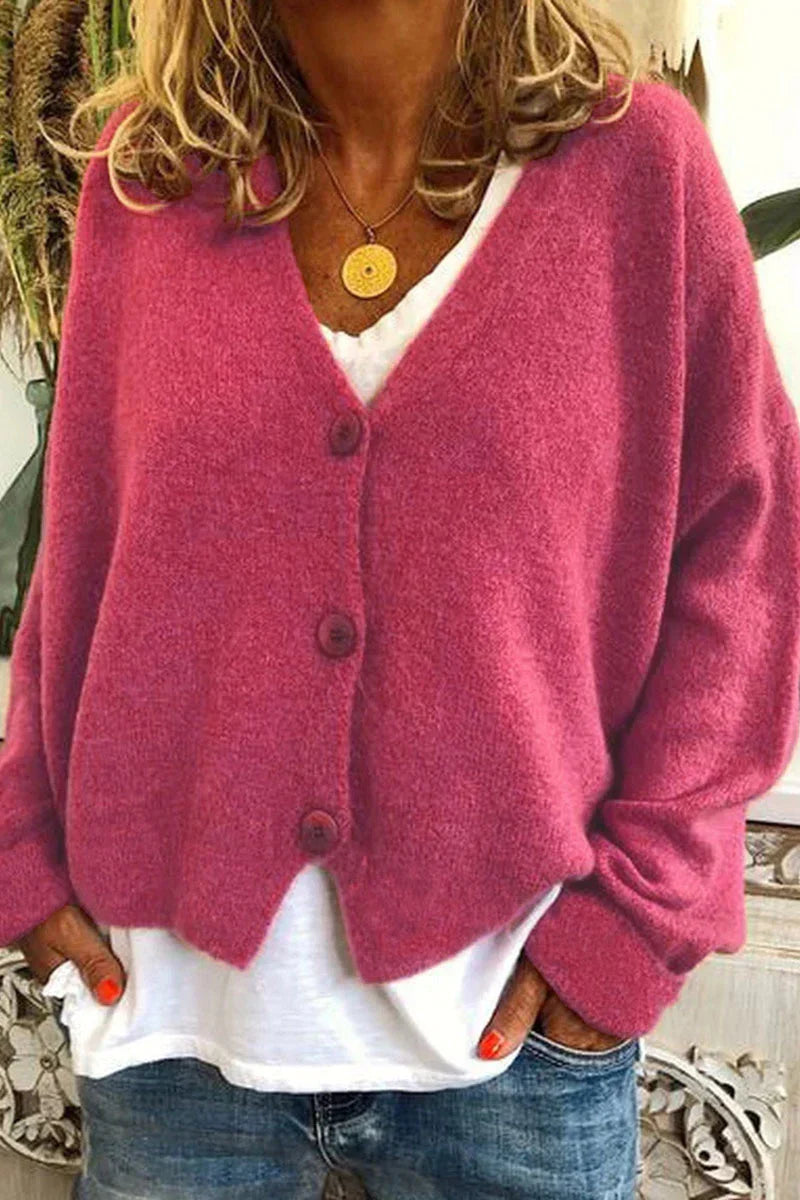 Femme portant un cardigan rose en laine avec boutons, sur un t-shirt blanc et un jean. Mode automne, style décontracté, tendance féminine.