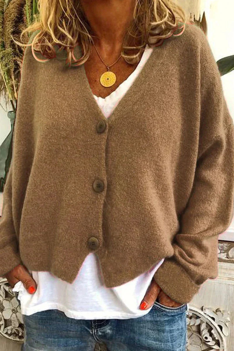 Femme portant un cardigan marron en laine avec boutons, sur un t-shirt blanc, et un collier doré. Mode automne, style décontracté, tendance.