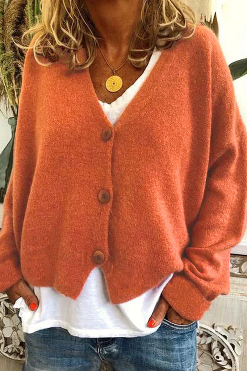 Femme portant un cardigan orange en laine avec boutons, sur un t-shirt blanc et un jean. Mode automne, style décontracté, tendance vêtements chauds.