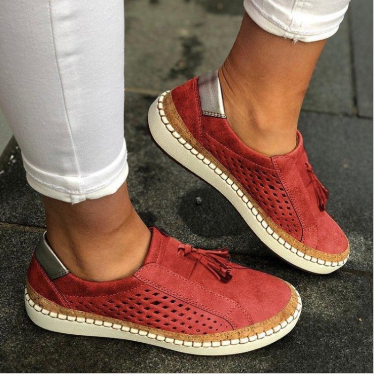 Chaussures rouges en daim avec semelle blanche, perforations et pompons, portées avec un pantalon blanc. Mode décontractée, tendance chaussures femme.
