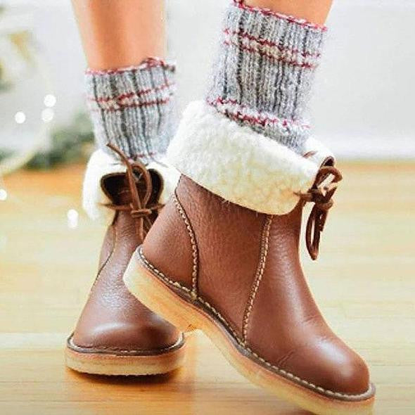 Bottes en cuir marron avec doublure en fourrure blanche, portées avec des chaussettes en laine grise. Mode hiver, chaussures confortables.