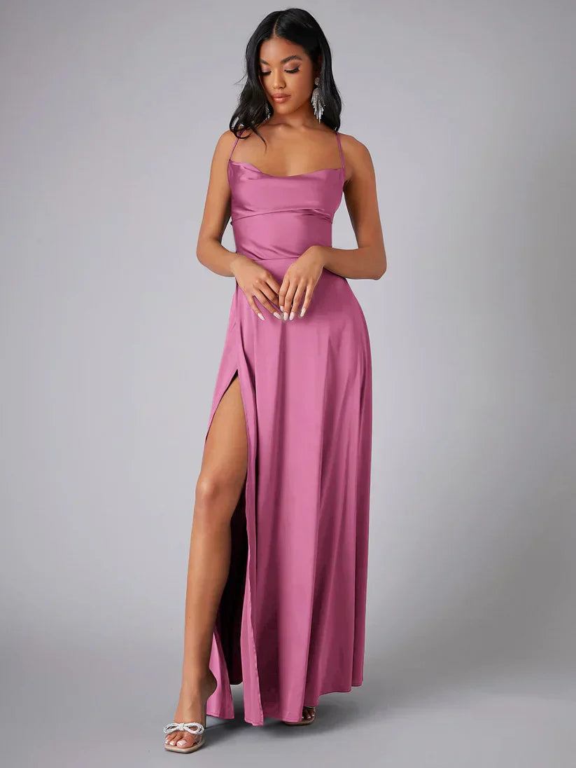 Femme en robe longue rose avec fente, posant élégamment. Robe de soirée élégante, mode féminine, style glamour, talons argentés.