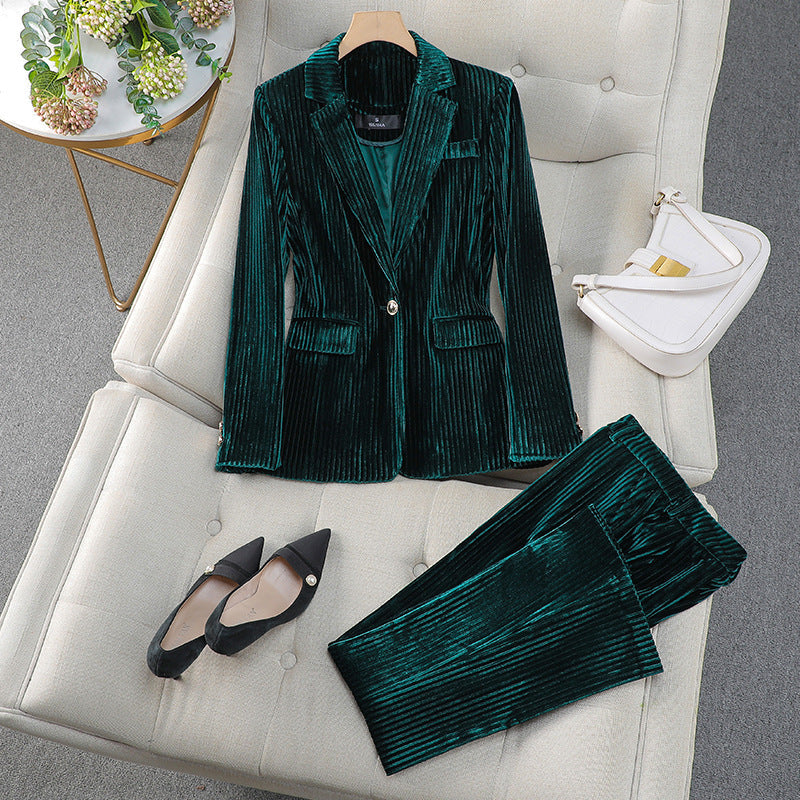 Costume en velours vert émeraude sur canapé beige, accompagné de chaussures noires et sac blanc. Mode élégante, tenue chic pour femme.