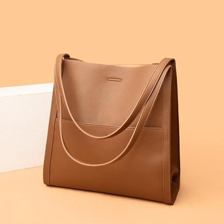 Sac à main en cuir marron élégant sur fond beige, design minimaliste, anses longues, parfait pour mode féminine, accessoires tendance.