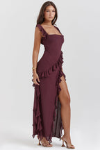 Robe longue bordeaux élégante avec volants, fente haute, portée par une femme. Mode féminine, tenue de soirée chic, style glamour.
